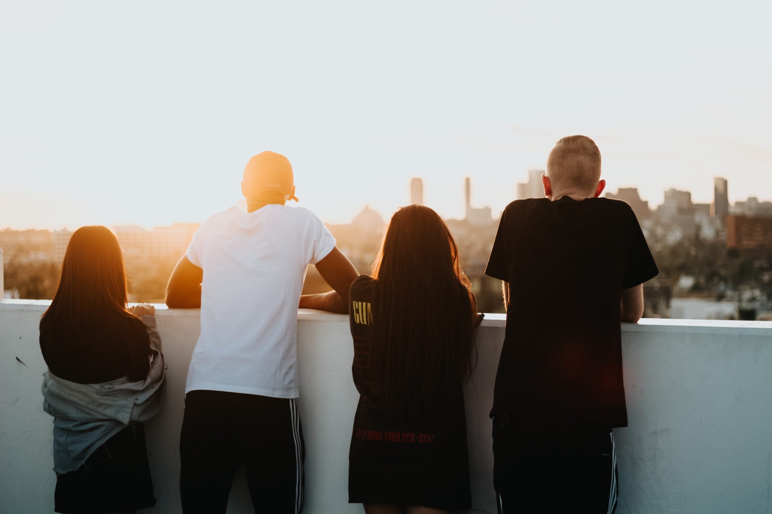 4 personnes regardant un coucher de soleil derrière un muret